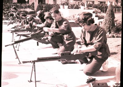 Several Vietnamese women are loading up guns up in a line.