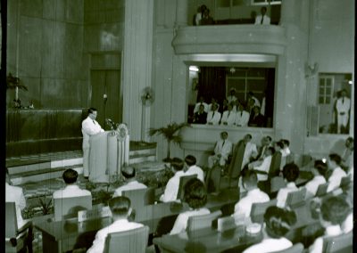 A man is standing at the podium as a crowd listens on.
