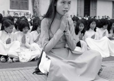 A woman is praying, many others are seen praying behind her in a line
