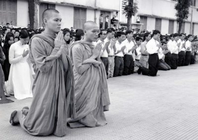 Two monks are seen praying, others are seen praying behind them
