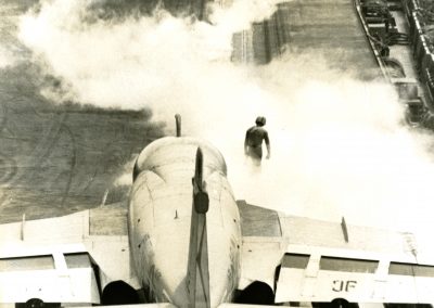 Steam is seen as a fighter jet just launched off an aircraft carrier. Man seen standing in the smoke
